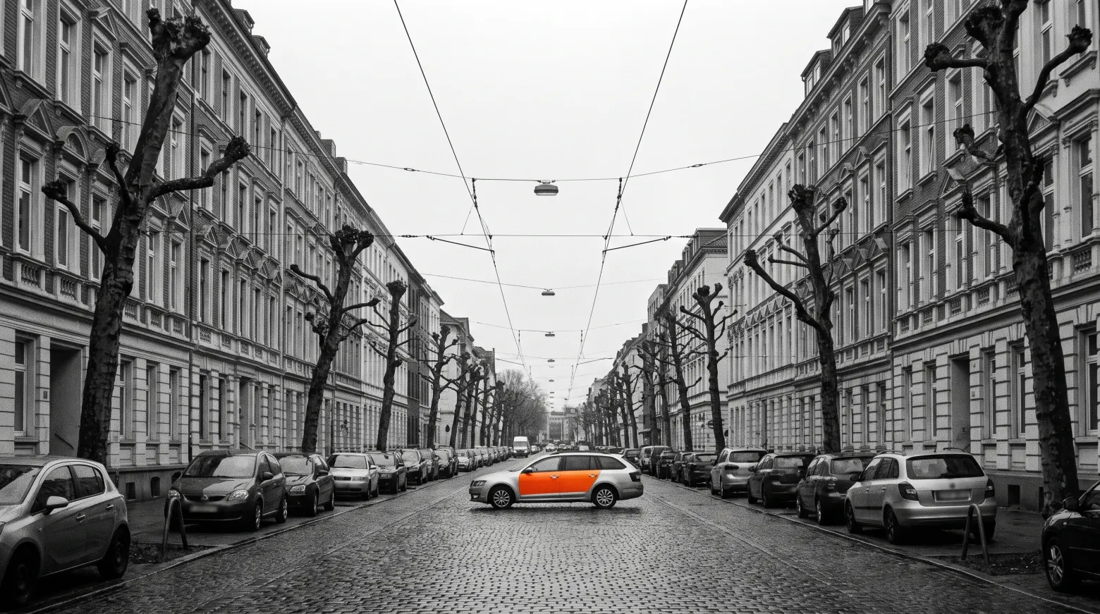 Straßenzug in Düsseldorf in Graustufen, weit hinten ein einzelnes farbig foliertes Fahrzeug.