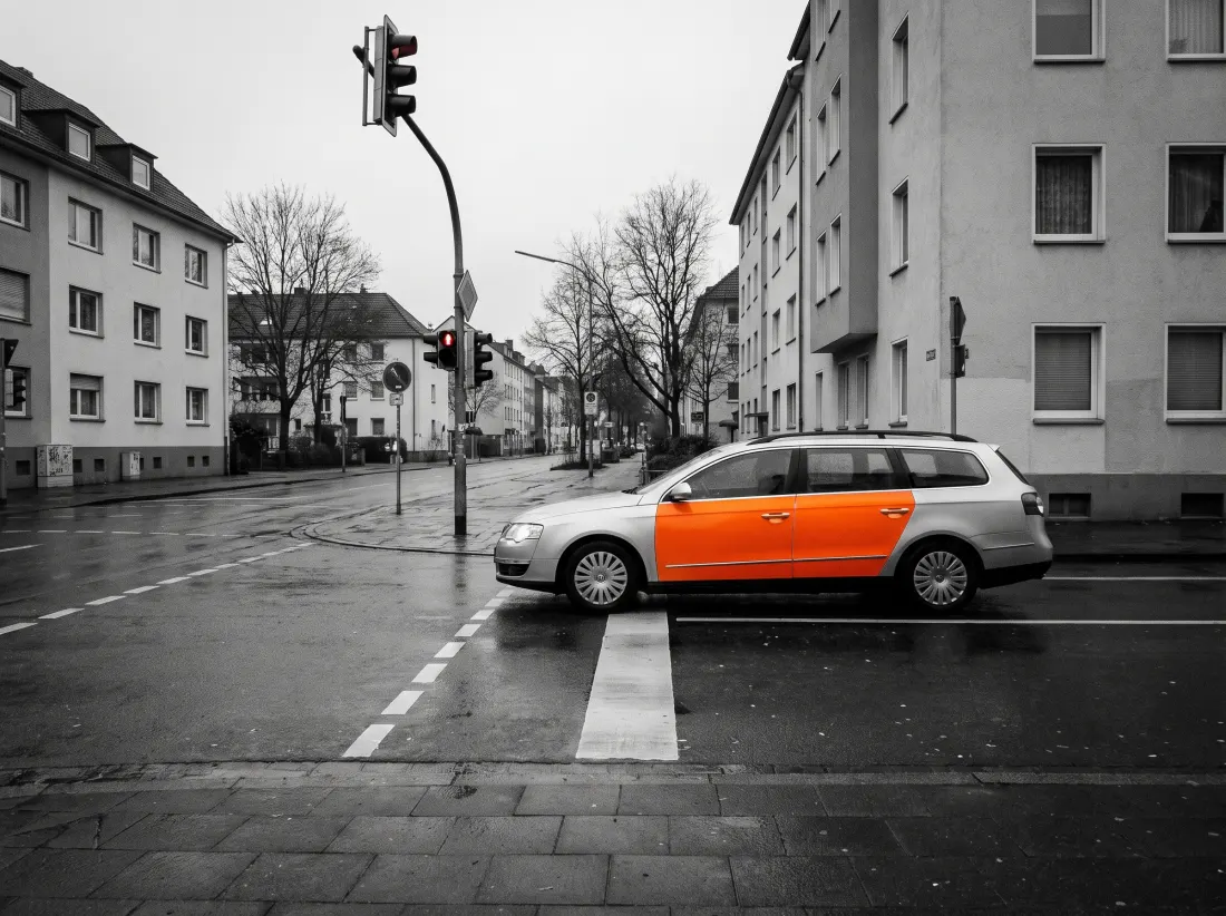 Ein teilfoliertes Fahrzeug wartet an einer roten Ampel, die Umgebung ist grau.